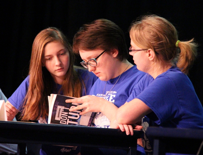Sandy Creek high school students (from left) Emily Smith, Olivia Bauer and Madeline Yousey successfully challenge one of the answers on their way to a perfect score in the district's adults versus students Battle of the Books competition.