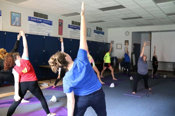 Kit Sheehan, (at right center) a certified yoga instructor and science teacher at the high school, leads students in a yoga class at the school.