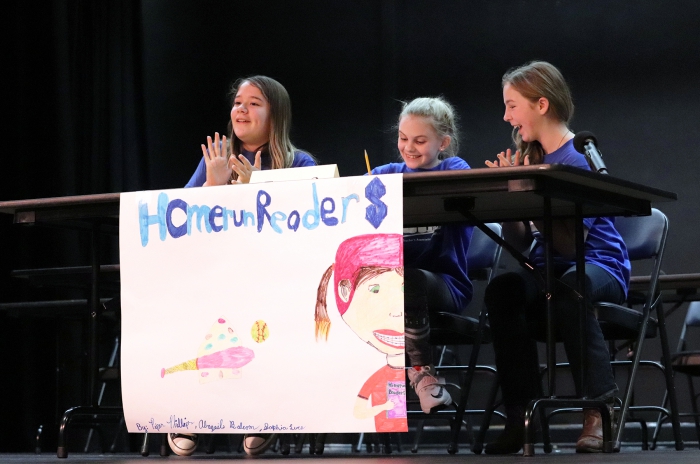 Sandy Creek students Piper Phillips, Abagail Balcom, Sophia Luce react in excitement to answering a question correctly during the "Students Verses Staff" Battle of the Books competition.