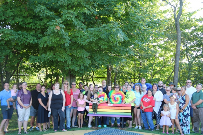 Family, friends, teachers and faculty attend a Buddy Bench dedication ceremony at the Sandy Creek Elementary School playground.