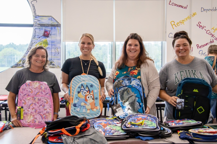 Stuff-A-Bus volunteers smile with backpacks.